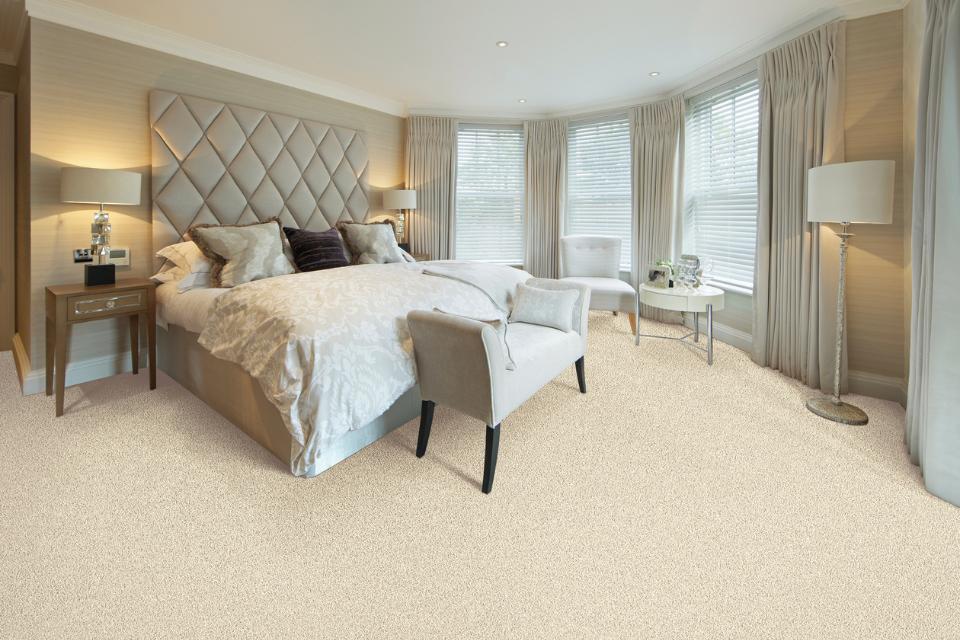 cream carpet in bedroom with beige bedframe and matching decor.